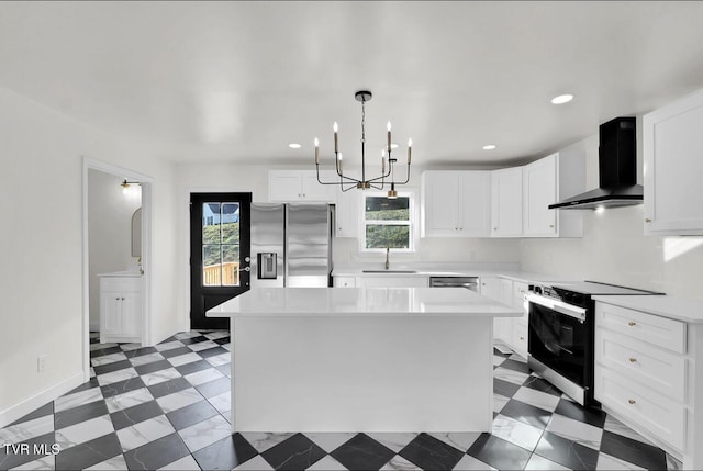 kitchen featuring stainless steel appliances, light countertops, white cabinetry, a kitchen island, and wall chimney exhaust hood