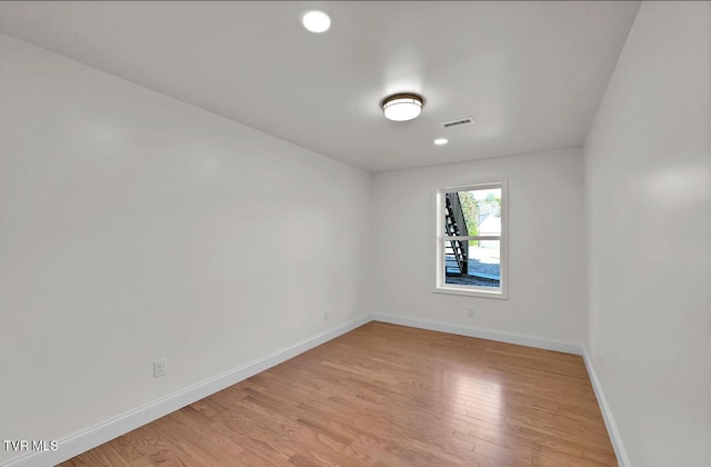 empty room with visible vents, light wood-style flooring, and baseboards