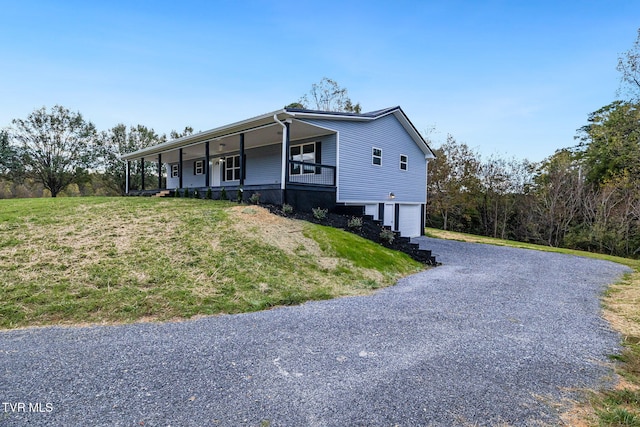 view of front of property with a garage, driveway, a porch, and a front lawn