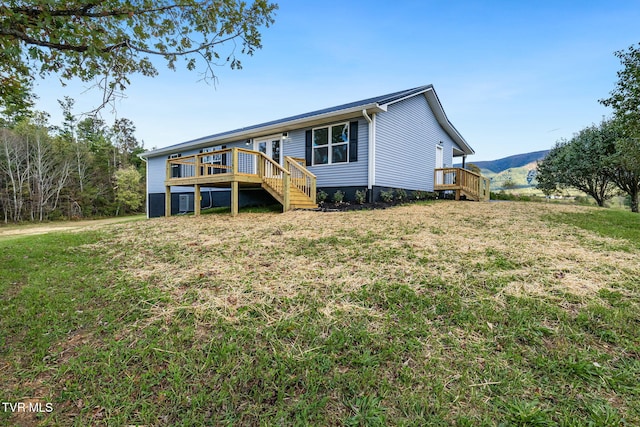 view of front facade featuring a front yard, a deck with mountain view, and stairs