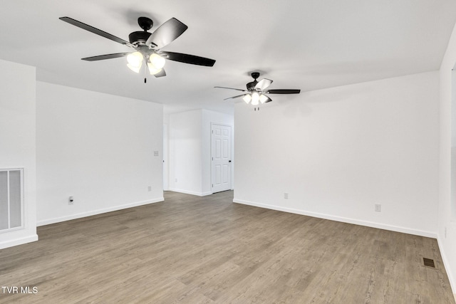 spare room with a ceiling fan, baseboards, visible vents, and wood finished floors