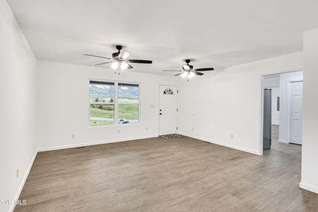 empty room featuring wood finished floors, a ceiling fan, and baseboards