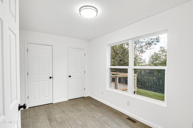 unfurnished bedroom featuring baseboards, visible vents, and wood finished floors