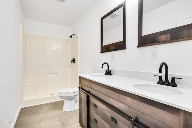 bathroom with toilet, double vanity, a sink, and wood finished floors