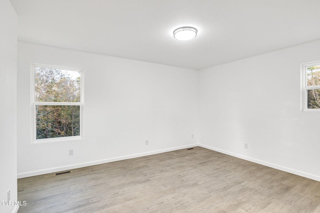 empty room featuring visible vents, light wood-style flooring, and baseboards