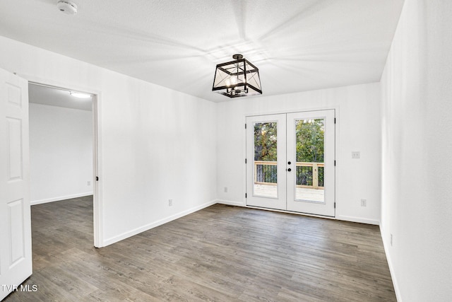 unfurnished dining area with baseboards, dark wood finished floors, a textured ceiling, and french doors