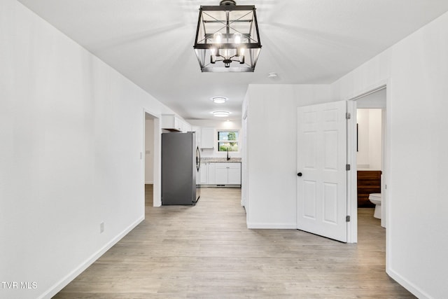 unfurnished dining area with light wood finished floors, baseboards, and a notable chandelier