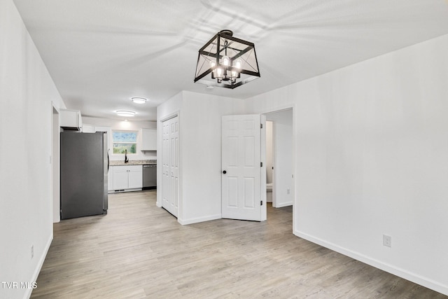 interior space featuring light wood-style flooring, baseboards, and a sink