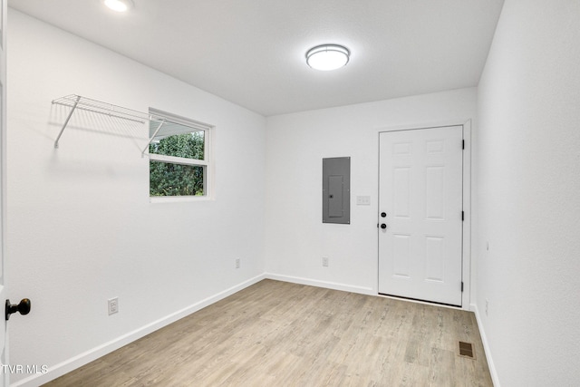 empty room with light wood finished floors, visible vents, electric panel, and baseboards