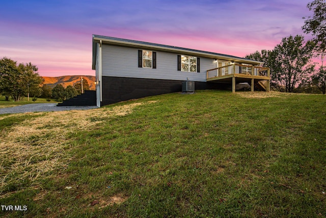 rear view of house with a deck with mountain view, a yard, and central AC unit