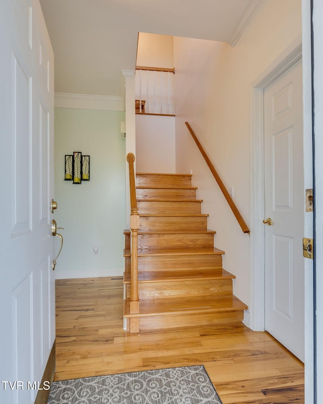 stairs with ornamental molding and wood finished floors