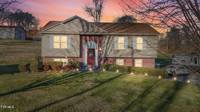 bi-level home with brick siding and a yard