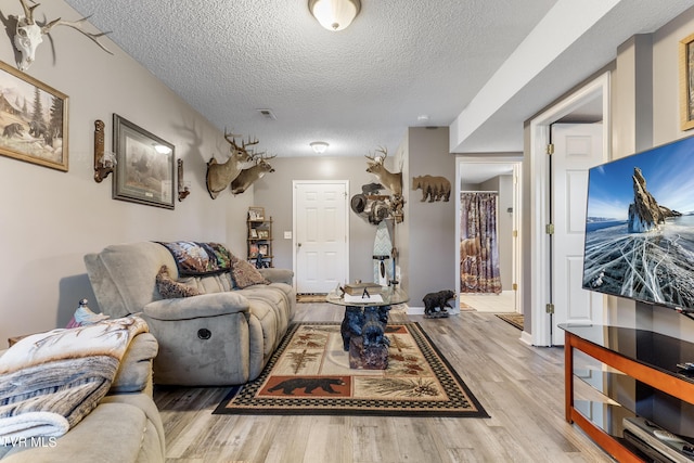 living room featuring a textured ceiling, visible vents, and wood finished floors