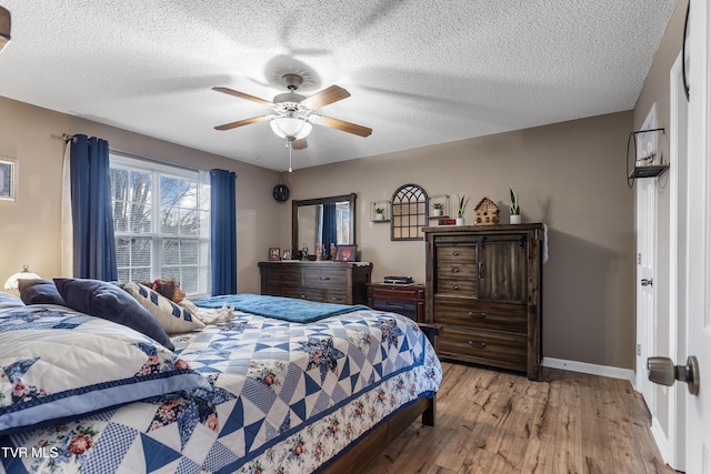 bedroom featuring a textured ceiling, wood finished floors, a ceiling fan, and baseboards