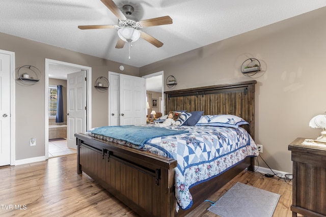 bedroom featuring light wood-type flooring, a textured ceiling, and ensuite bathroom