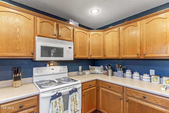 kitchen featuring white appliances, light countertops, a textured ceiling, and brown cabinetry