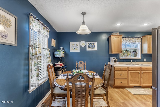 dining area with light wood-type flooring, baseboards, a textured ceiling, and recessed lighting