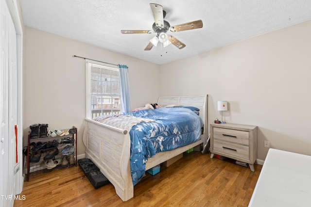 bedroom featuring baseboards, a textured ceiling, a ceiling fan, and light wood-style floors