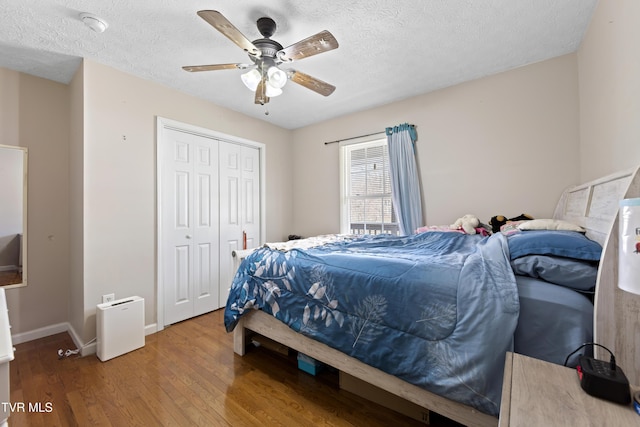 bedroom featuring a closet, ceiling fan, a textured ceiling, wood finished floors, and baseboards