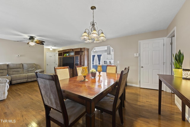dining room with dark wood-style floors, arched walkways, baseboards, and ceiling fan with notable chandelier