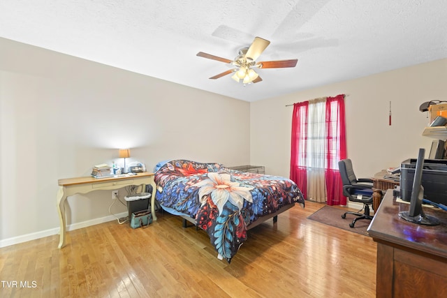 bedroom with a ceiling fan, a textured ceiling, baseboards, and wood finished floors