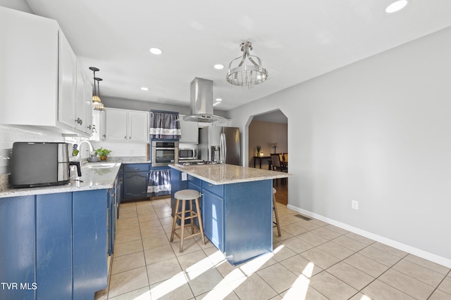 kitchen featuring arched walkways, appliances with stainless steel finishes, island exhaust hood, a kitchen bar, and white cabinetry