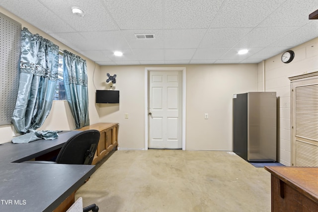 home office featuring a drop ceiling, visible vents, and concrete block wall