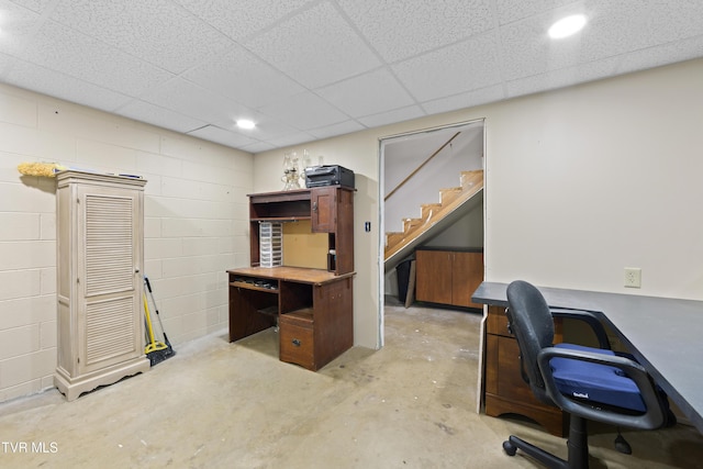 office with concrete flooring, concrete block wall, and a paneled ceiling