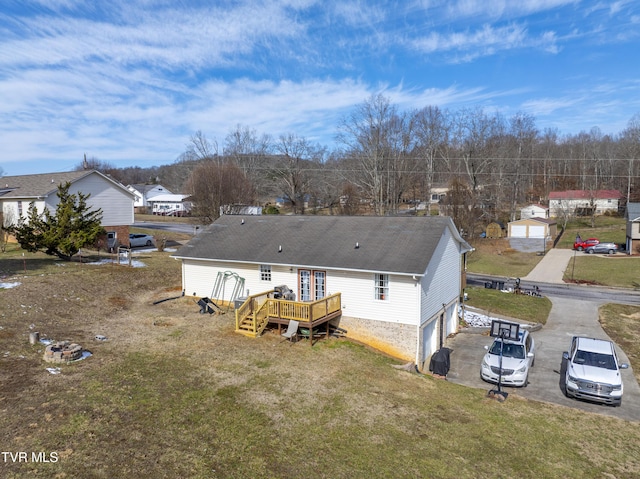 back of property with a lawn, a residential view, aphalt driveway, an attached garage, and a wooden deck