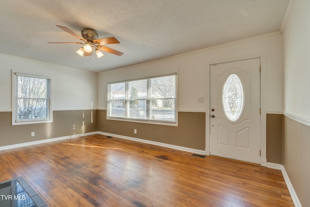 foyer with wainscoting, visible vents, plenty of natural light, and wood finished floors