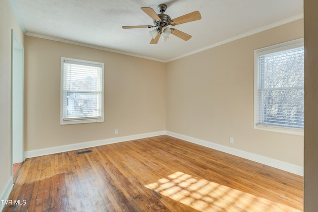 spare room featuring baseboards, visible vents, light wood-style flooring, and crown molding