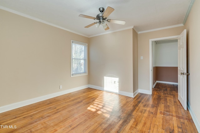 spare room with a ceiling fan, baseboards, ornamental molding, and wood finished floors