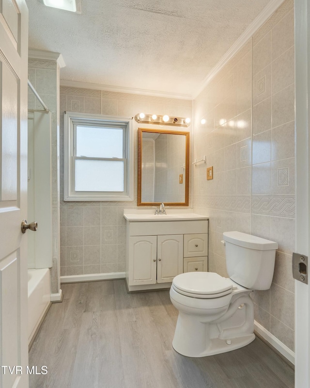 bathroom with toilet, tile walls, a textured ceiling, and wood finished floors