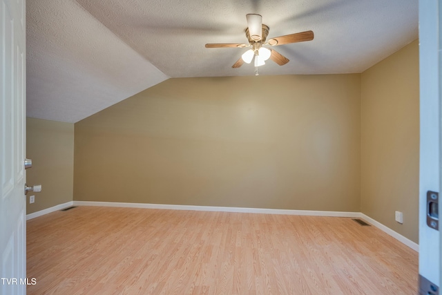 bonus room featuring a textured ceiling, ceiling fan, lofted ceiling, baseboards, and light wood finished floors