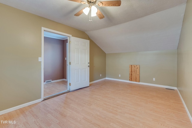 additional living space with light wood-style floors, lofted ceiling, visible vents, and baseboards