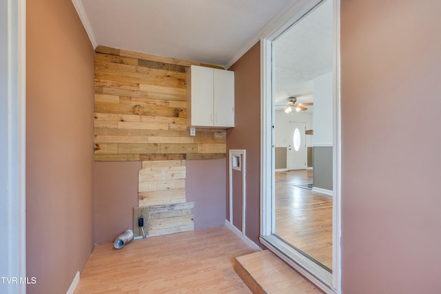 washroom featuring crown molding, light wood finished floors, wood walls, ceiling fan, and baseboards