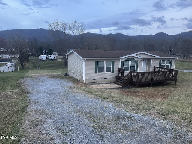 manufactured / mobile home featuring a front yard, crawl space, driveway, and a deck with mountain view