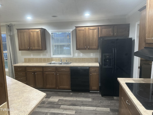 kitchen with a sink, light countertops, dark wood-style floors, black appliances, and crown molding