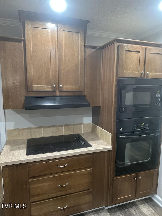 kitchen featuring black appliances, ornamental molding, and light countertops