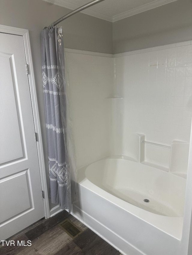 full bath with shower / tub combo, wood finished floors, visible vents, and crown molding