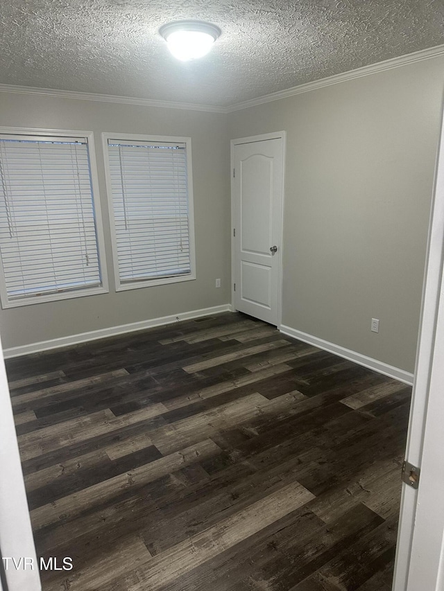 empty room with dark wood-style floors, ornamental molding, a textured ceiling, and baseboards