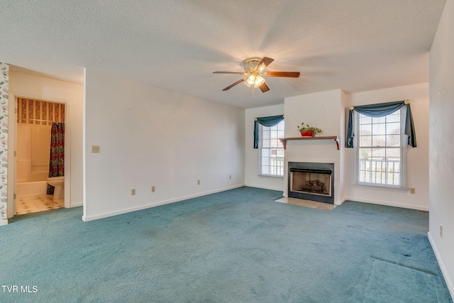 unfurnished living room featuring a fireplace with flush hearth, a wealth of natural light, carpet flooring, and a textured ceiling