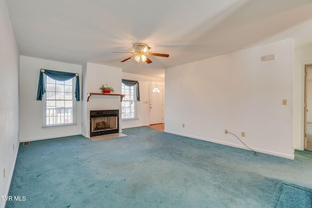 unfurnished living room featuring a fireplace with flush hearth, carpet flooring, baseboards, and a ceiling fan