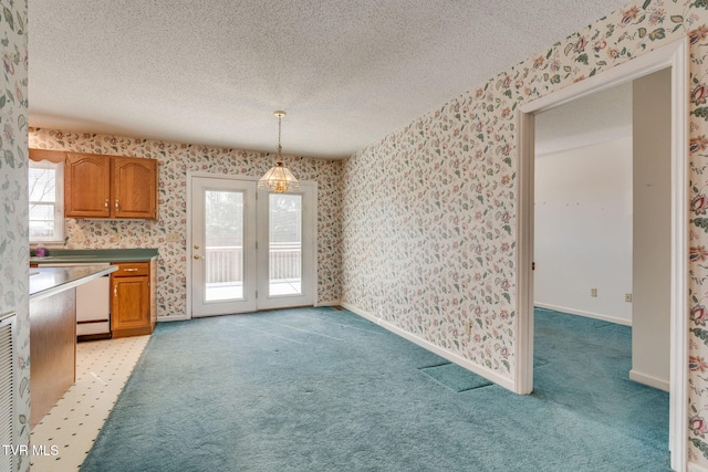 unfurnished dining area with light carpet, wallpapered walls, and a textured ceiling