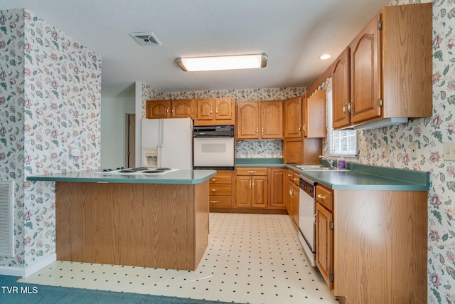 kitchen with brown cabinets, light floors, a sink, white appliances, and wallpapered walls