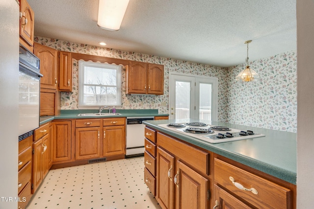 kitchen with white appliances, light floors, brown cabinetry, dark countertops, and wallpapered walls