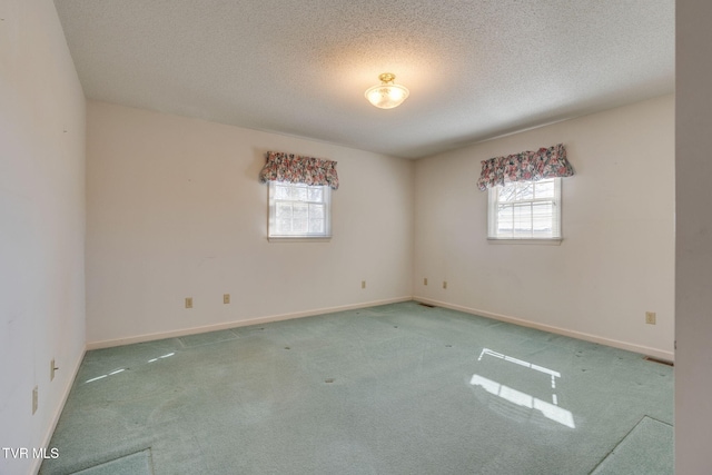 spare room featuring a textured ceiling, baseboards, and carpet flooring