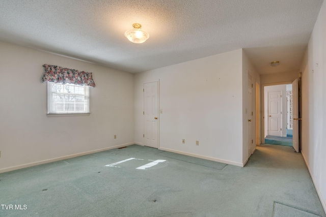 spare room featuring carpet, baseboards, and a textured ceiling