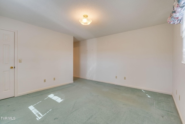 unfurnished room with a textured ceiling, baseboards, and carpet flooring