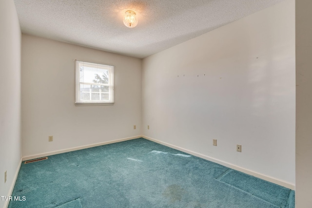 carpeted spare room featuring a textured ceiling, visible vents, and baseboards